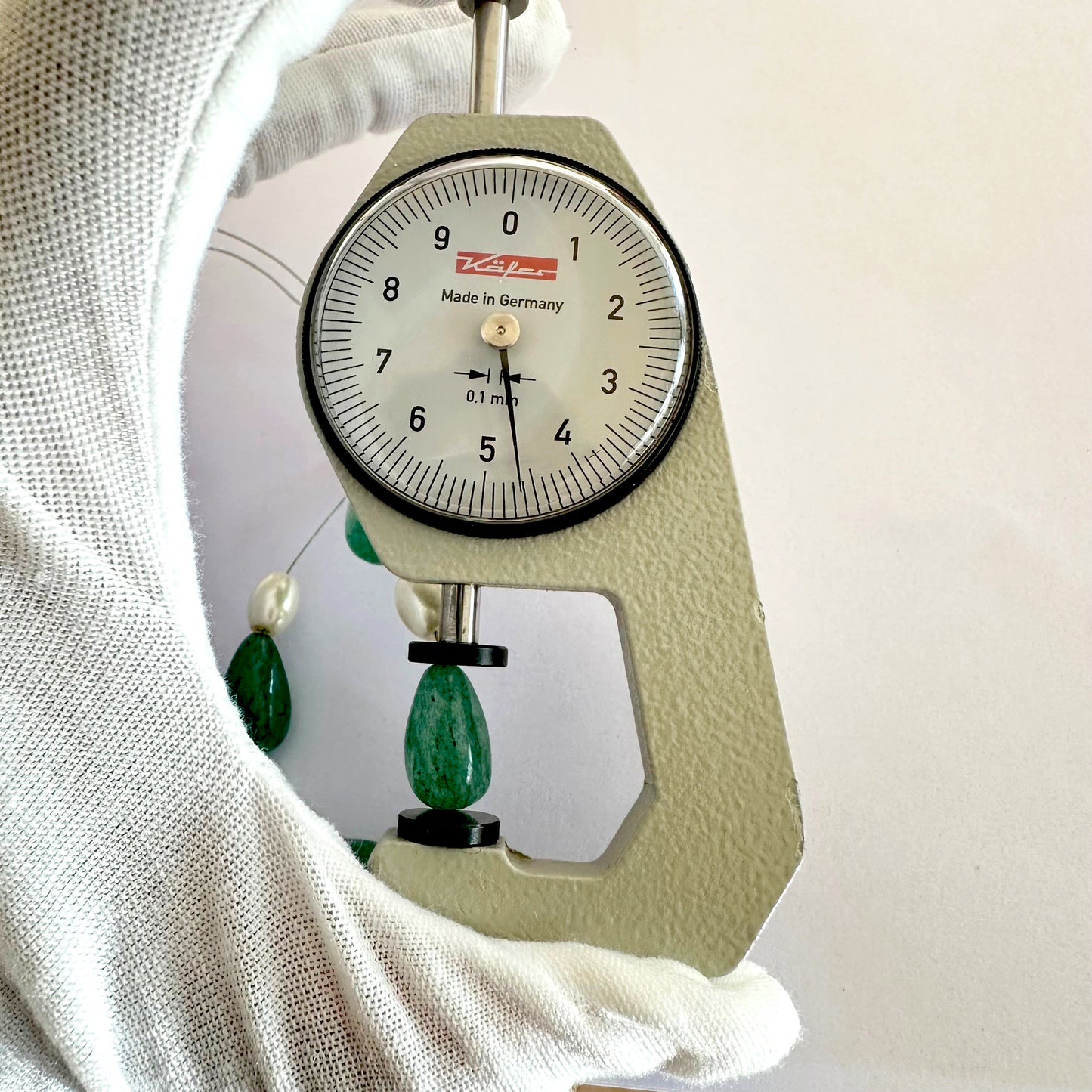 A dial gauge measures the Beryl Emerald teardrop gemstone.
