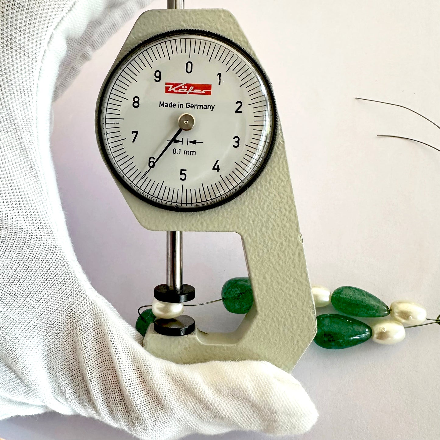 A dial gauge measures the oval pearl gemstone.