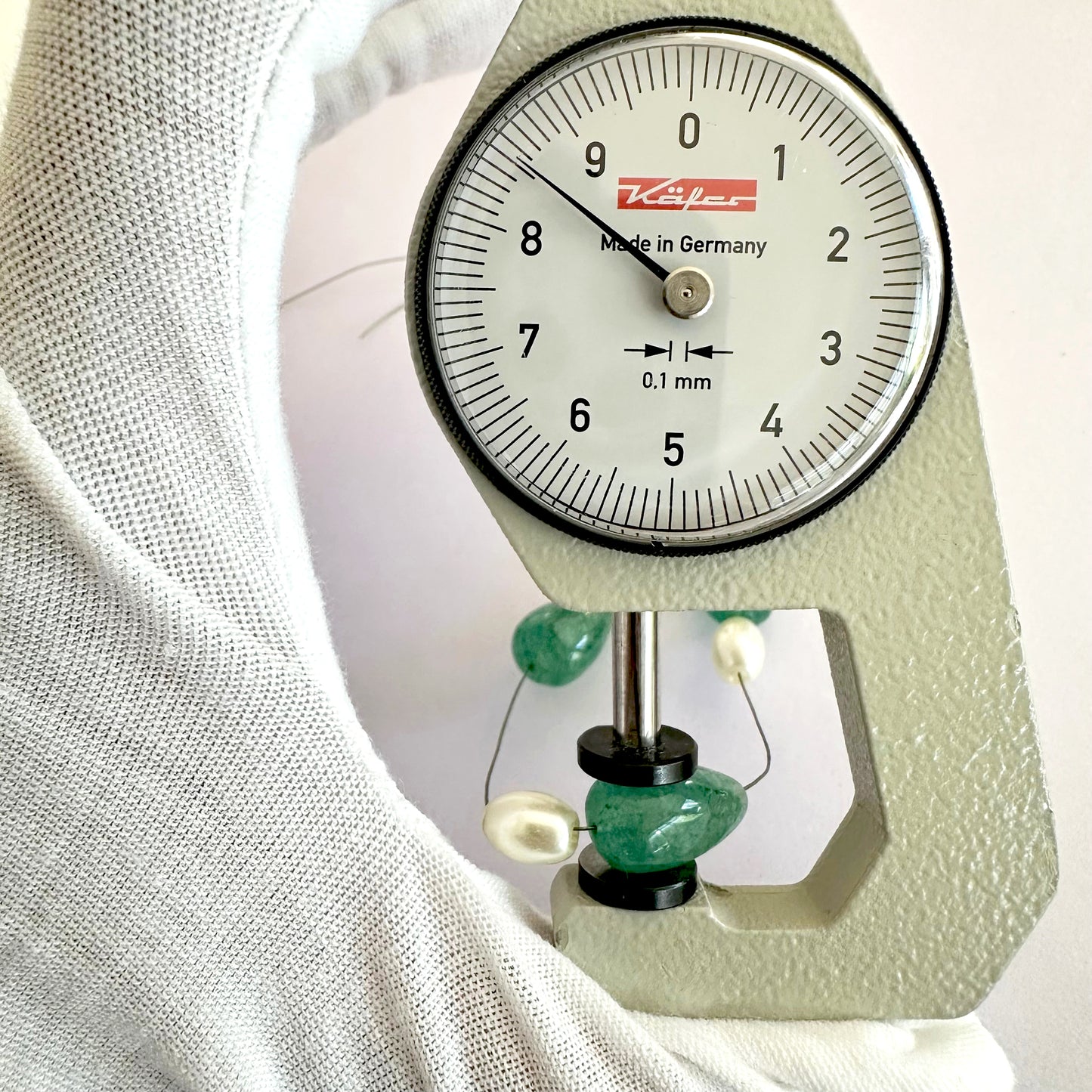 A dial gauge measures the Emerald gemstone.