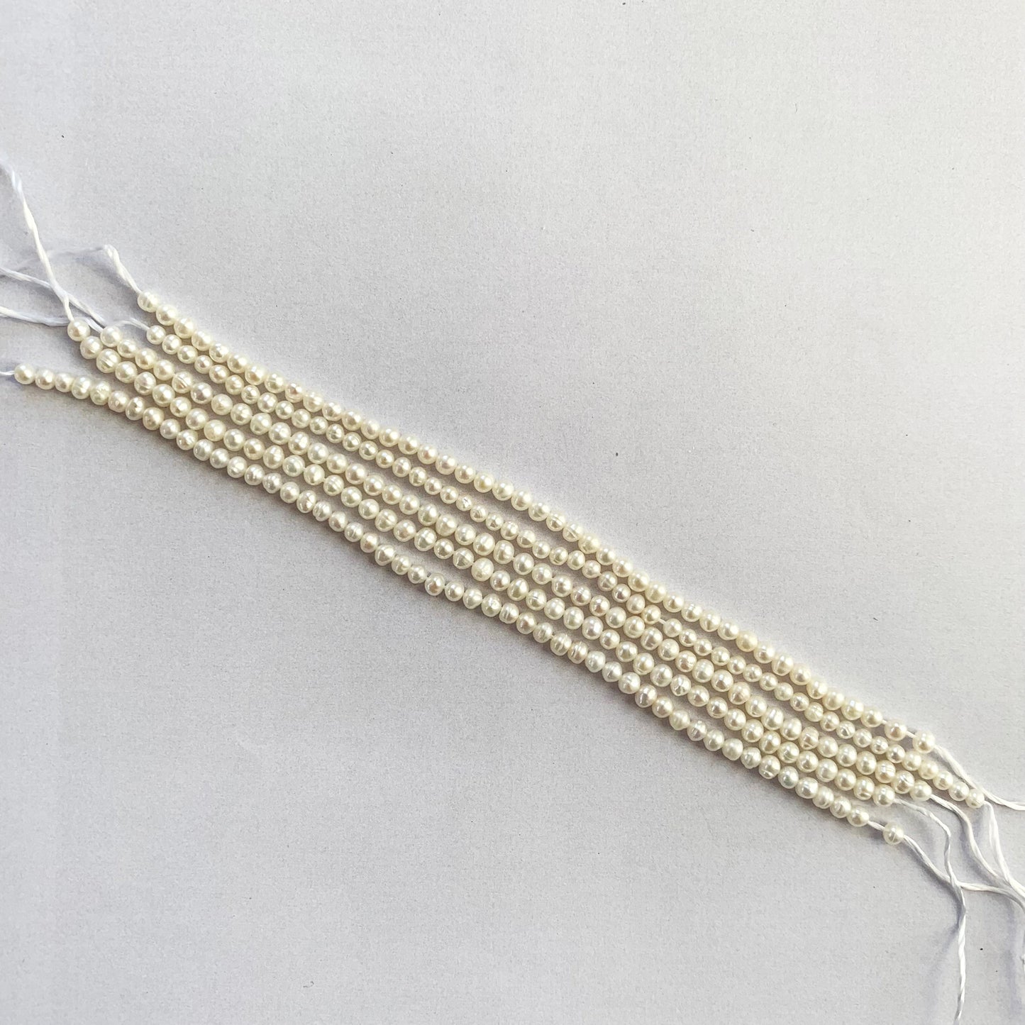 Smooth round pearls in creamy hues, 3.0-3.2mm, displayed with soft natural shine.