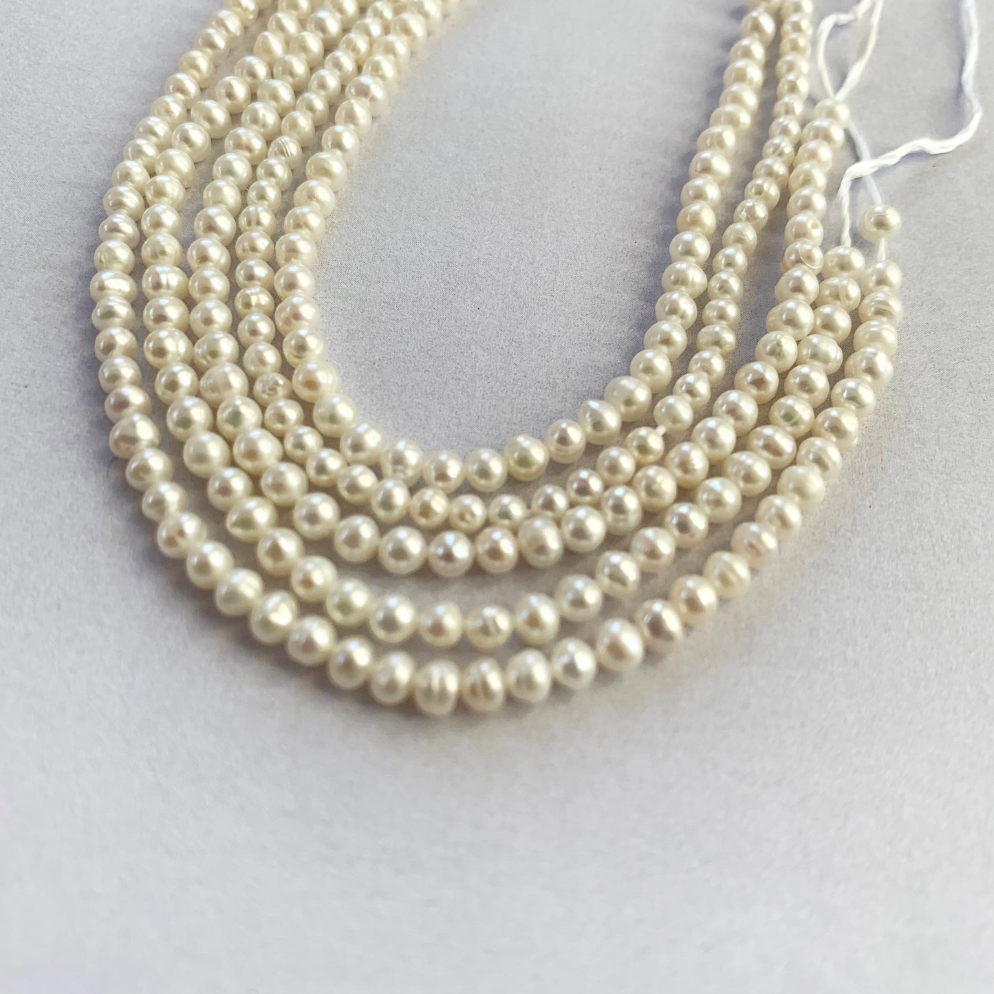 Neatly strung freshwater pearls in soft white tones, ideal for fine jewellery making.