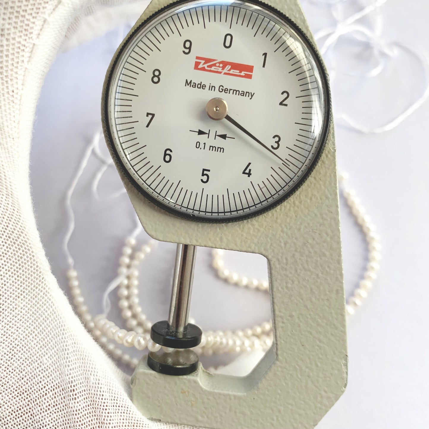 A dial gauge measures the Freshwater Pearl smooth round 3.0-3.2mm gemstone.