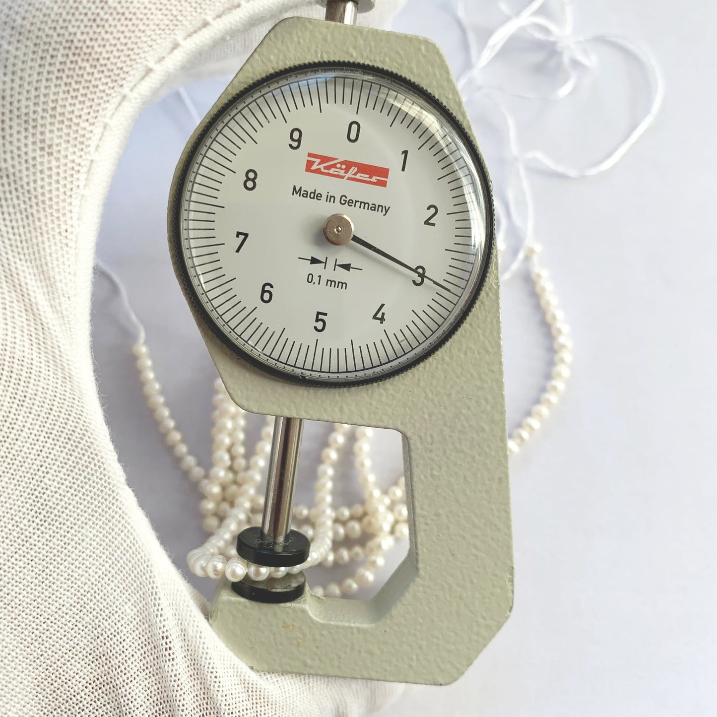 A dial gauge measures the Freshwater Pearl smooth round 3.0-3.2mm gemstone.