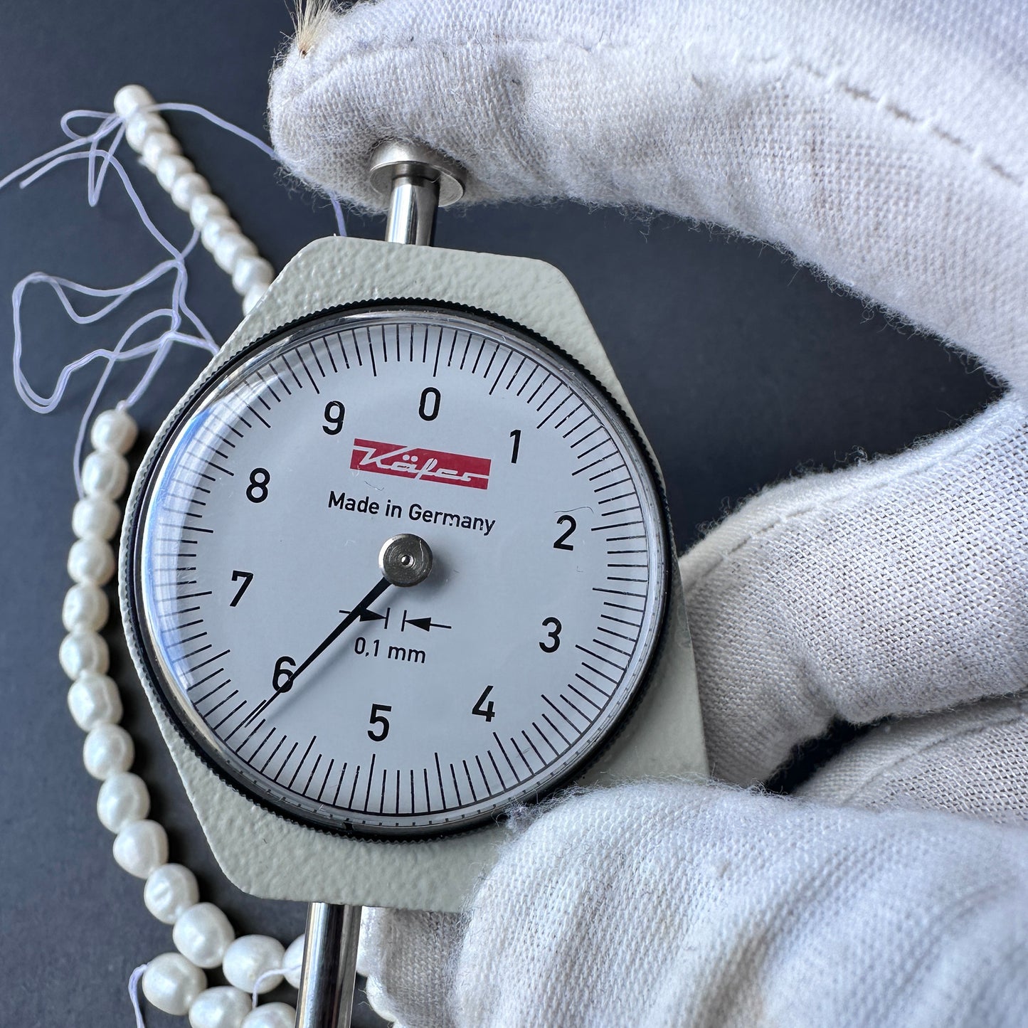 A dial gauge measures the freshwater pearl round 6mm gemstone.