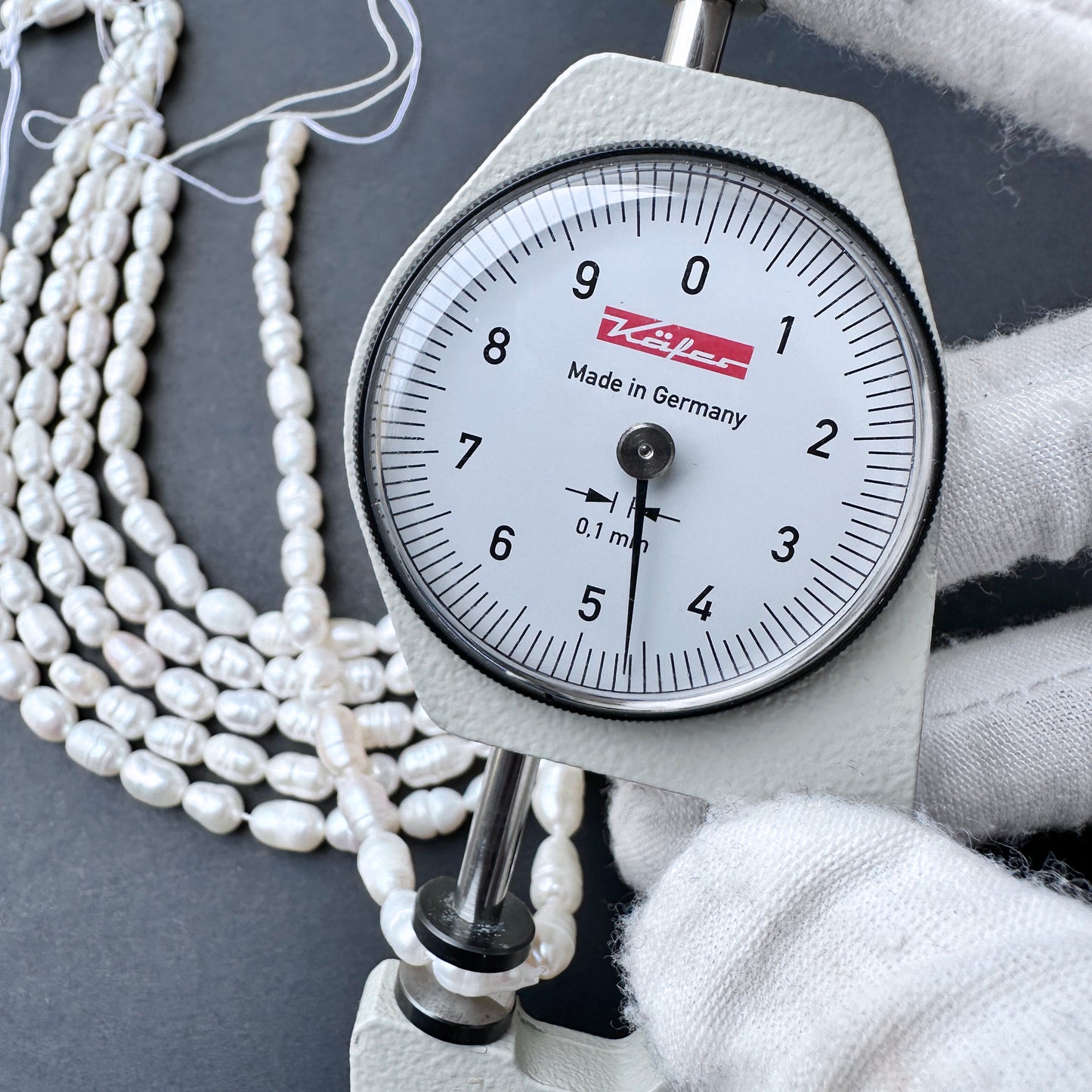 A dial gauge measures breadth of a baroque rice shaped Freshwater Pearl.