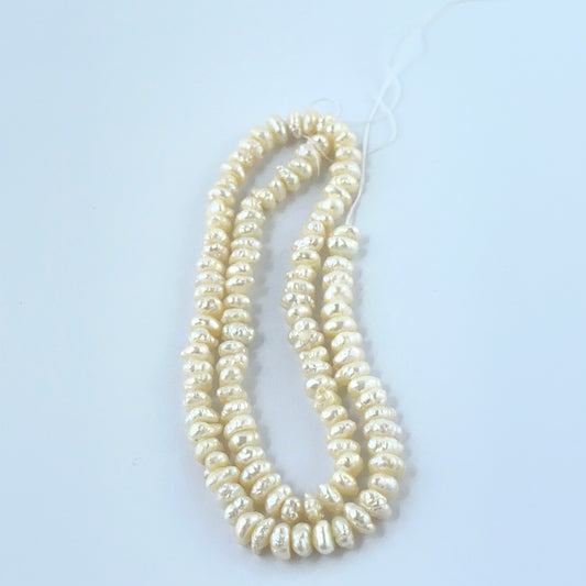 Close‑up of Freshwater Pearl stone beads arranged in a strand with textured surfaces.