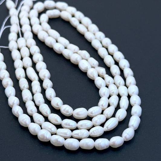 Close‑up of 4mm and 4.2–2.5mm freshwater pearl beads showing smooth surfaces ideal for natural gemstone beads for DIY jewellery.