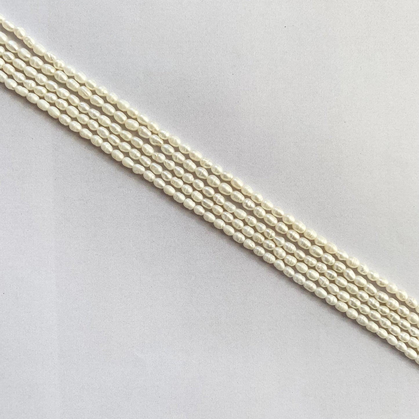 Glossy rice-shaped freshwater pearls radiating soft white hues on a delicate string.