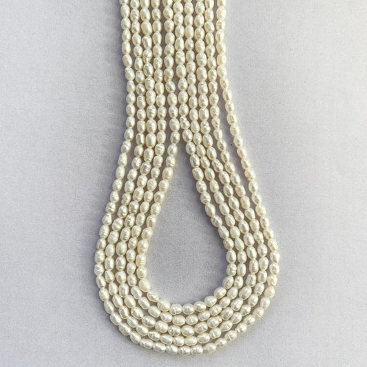Smooth oval freshwater pearls with 3.0-3.3mm sizing displayed in uniform rows.
