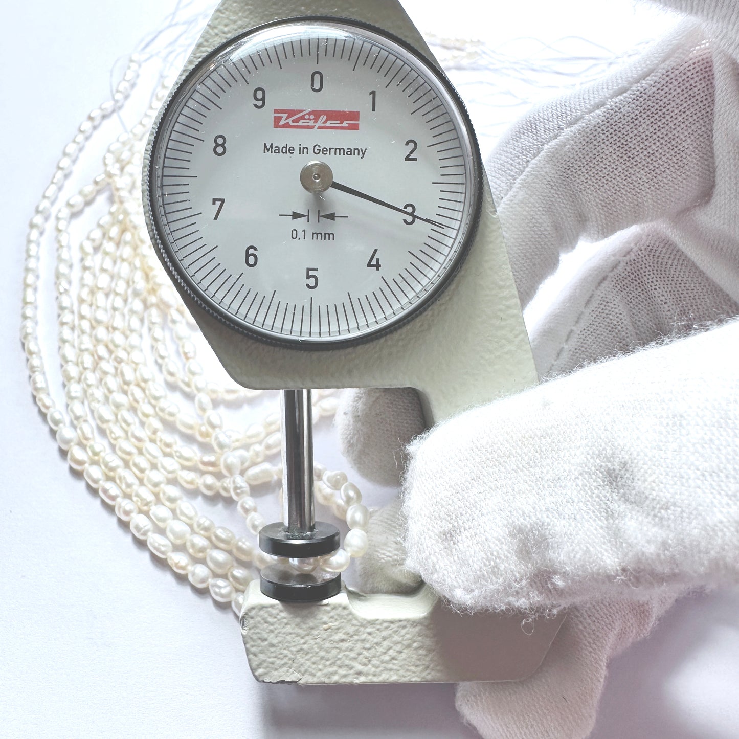 A dial gauge measures the Freshwater Pearl rice cut 3mm gemstone.