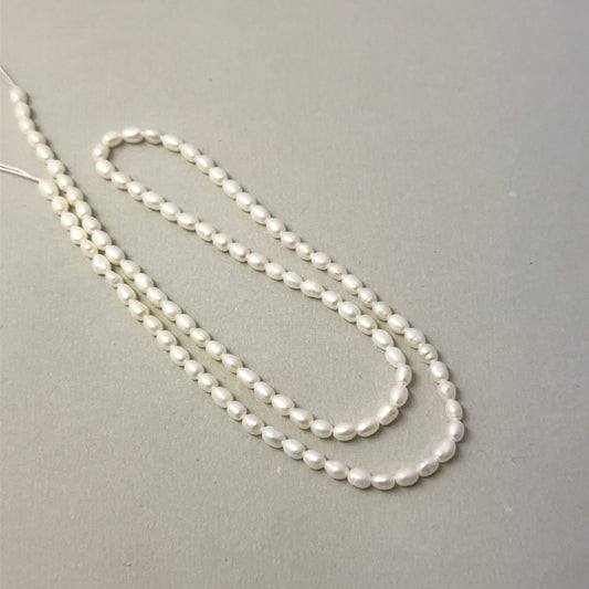 Close view of polished Freshwater Pearl smooth rice beads arranged on a 37cm strand for handmade jewellery components.
