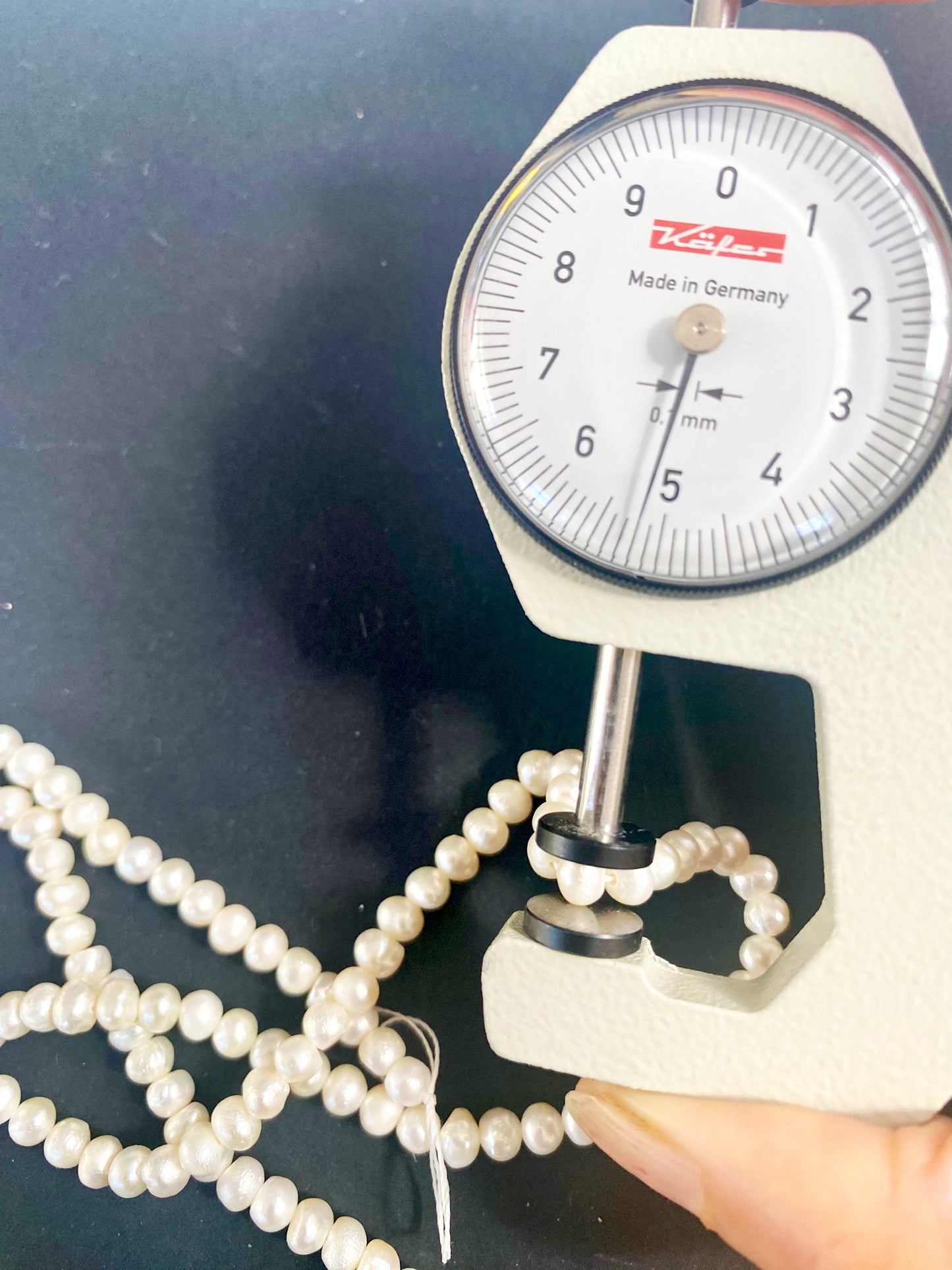 A dial gauge measures the Freshwater Pearl smooth rondelle 4.5–5mm gemstone.