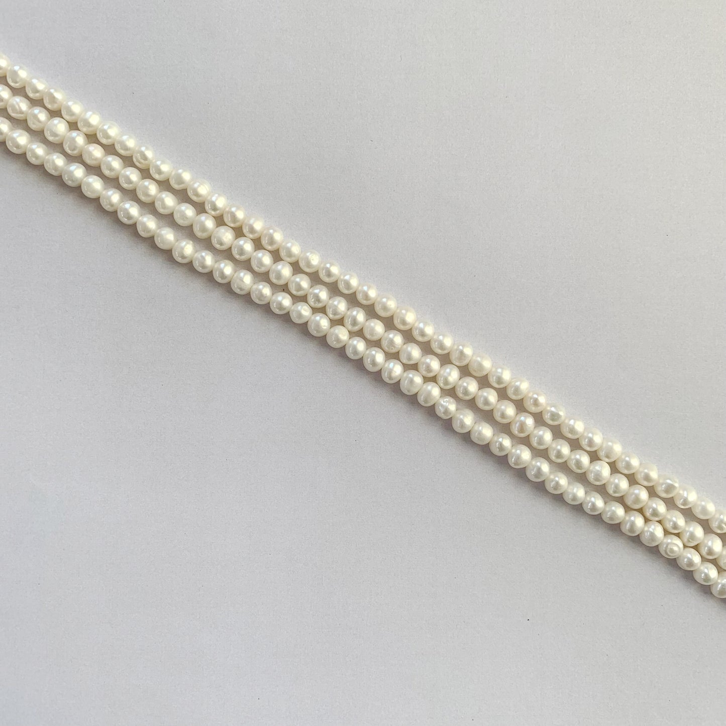 Glossy round freshwater pearls glowing under natural light on a 40cm necklace strand.