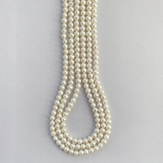 Soft white freshwater pearls with smooth round cut, 4.5-5.0mm sizes arranged on a strand.