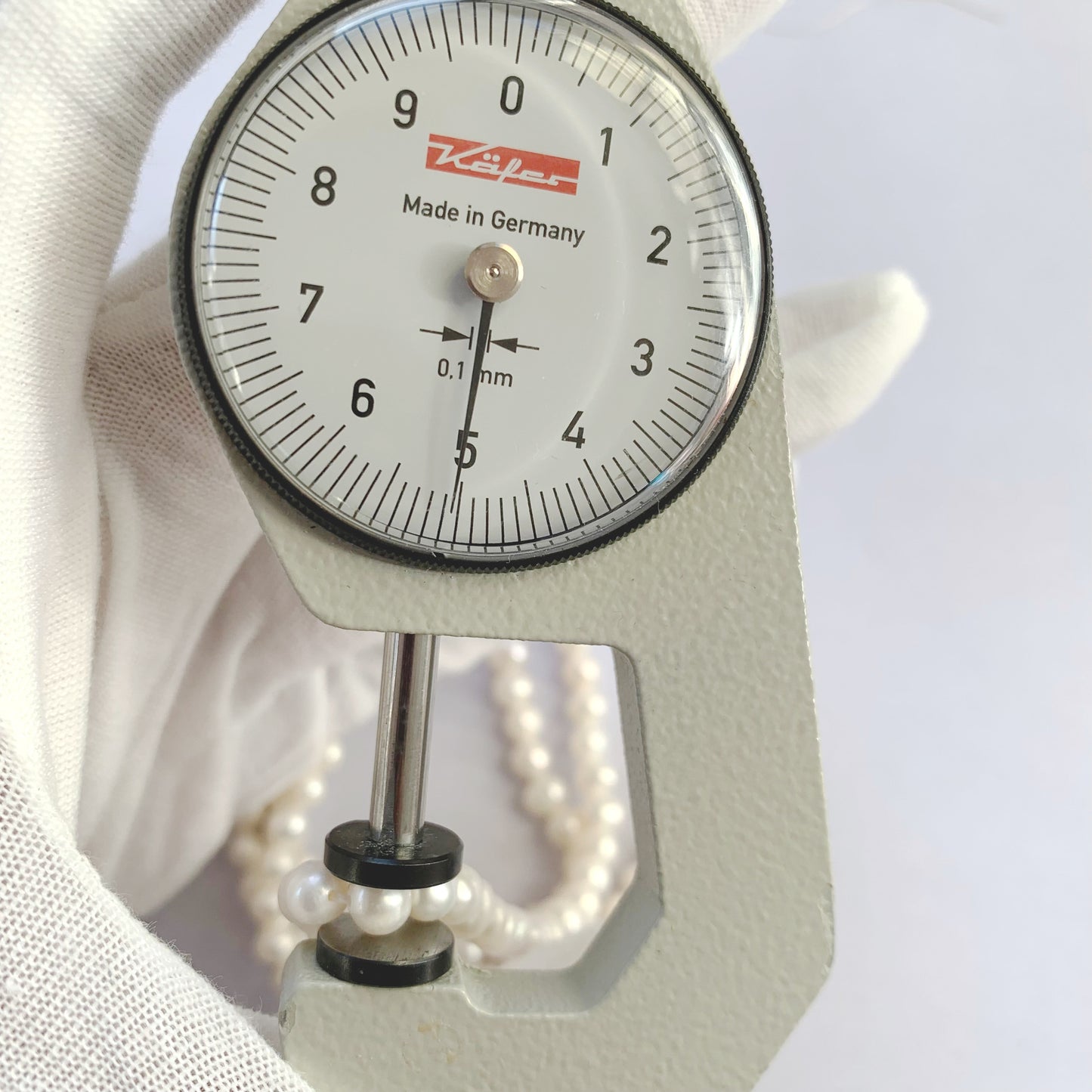 A dial gauge measures the Freshwater Pearl smooth round 4.5-5.0mm gemstone.