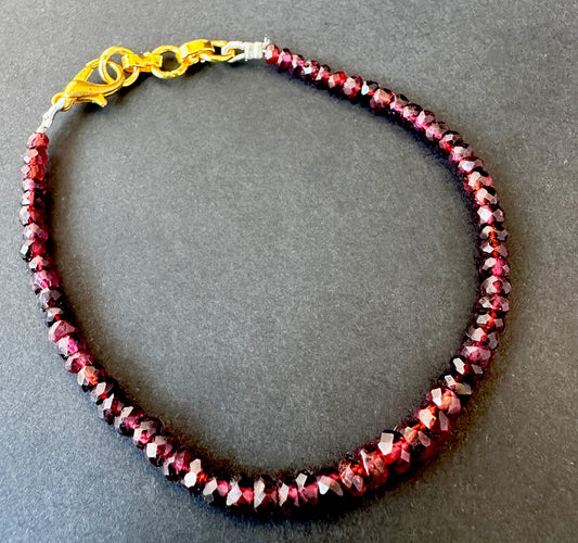 Close-up of garnet bracelet featuring faceted rondelle stone beads, deep red colour and polished shine.