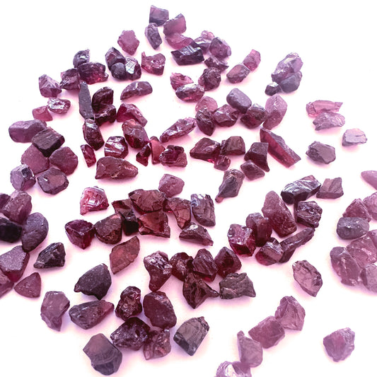 Close-up of raw garnet gemstones showing organic surface and rich crimson tones.