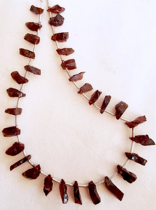 Close-up of 31 garnet stones with irregular cuts, highlighting their rich hue and organic sparkle.