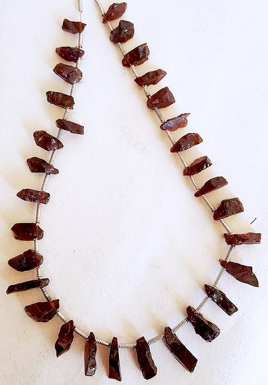 Garnet gemstones in varied 7x4mm to 13x5mm sizes, laid out to emphasize their natural shine and quality.