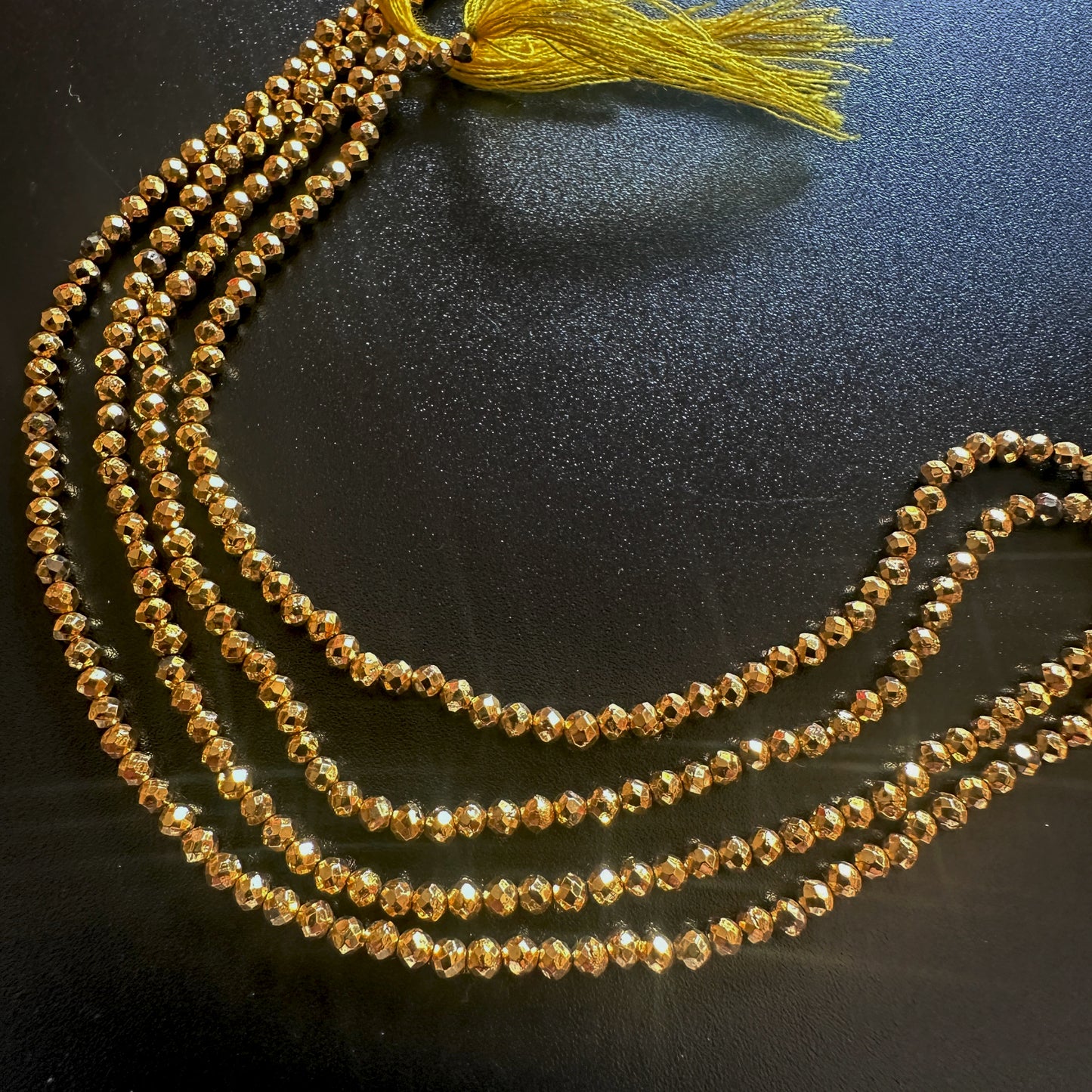 Close-up of 2.5mm gold pyrite beads arranged in a neat faceted rondelle formation.