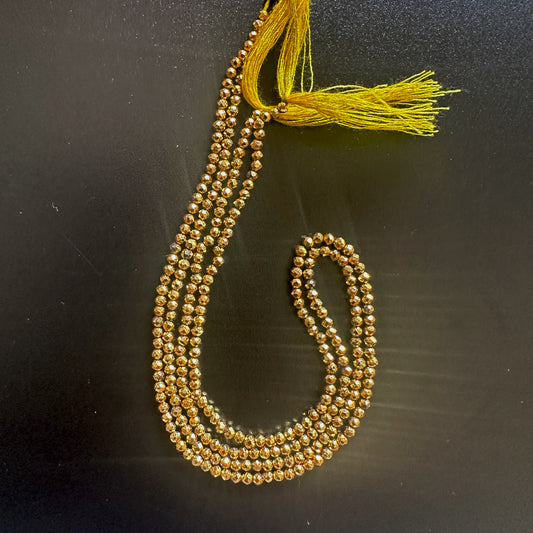 Faceted gold pyrite gemstones reflecting light with a smooth, polished surface.