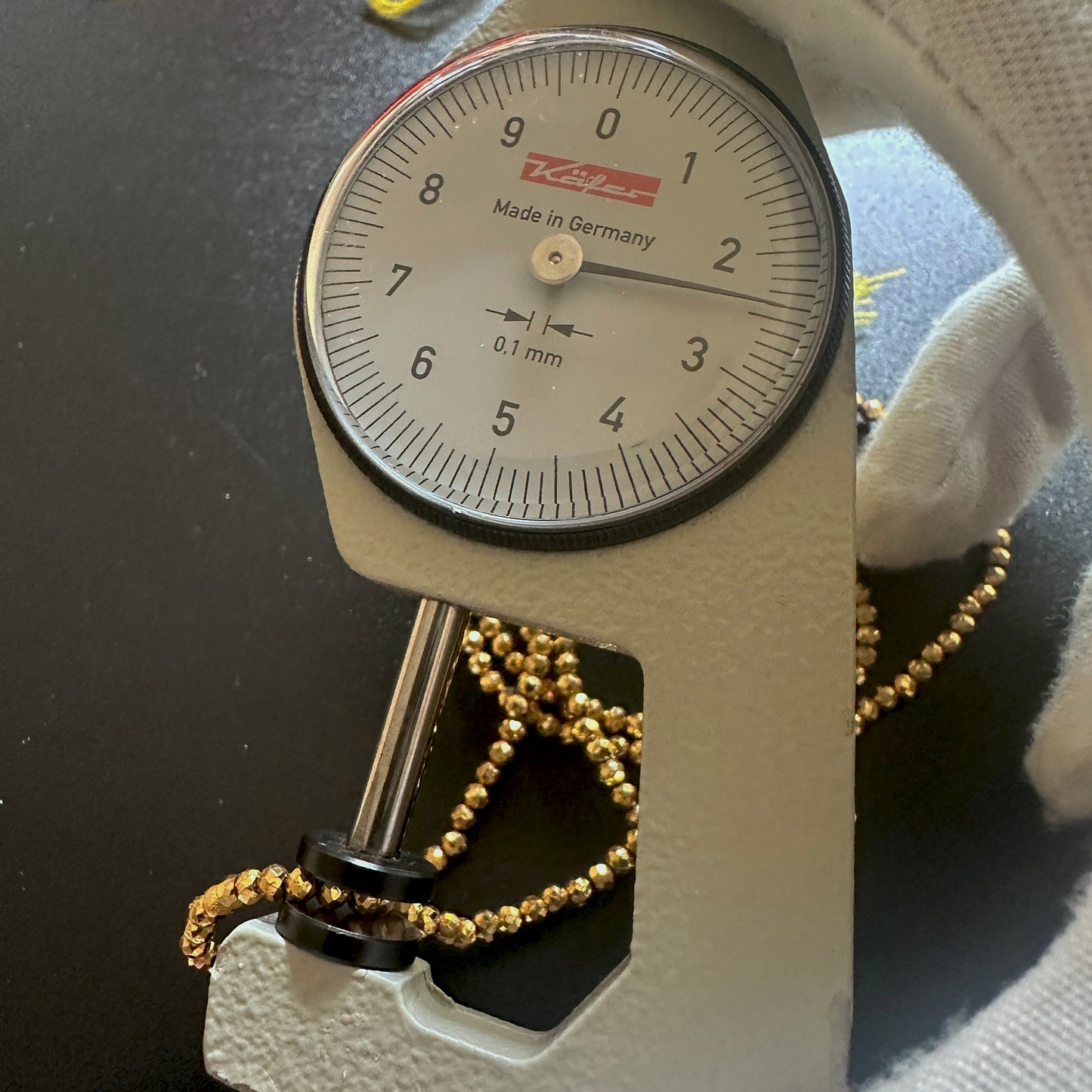 A dial gauge measures the gold pyrite faceted rondelle 2.5mm gemstone.