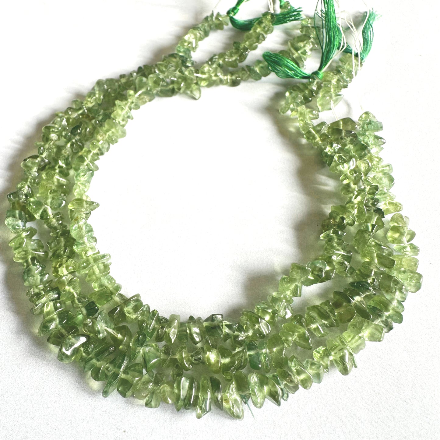 Glossy Green Apatite gemstone chips catching light to reveal their crystal texture.