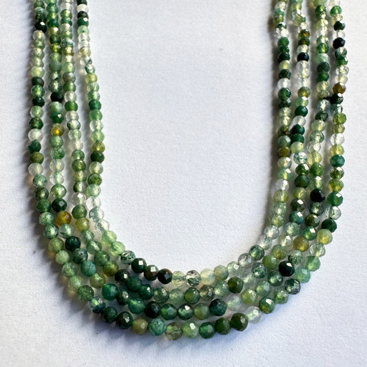 Green aventurine rondelle beads arranged in a strand, reflecting light with their faceted surfaces.