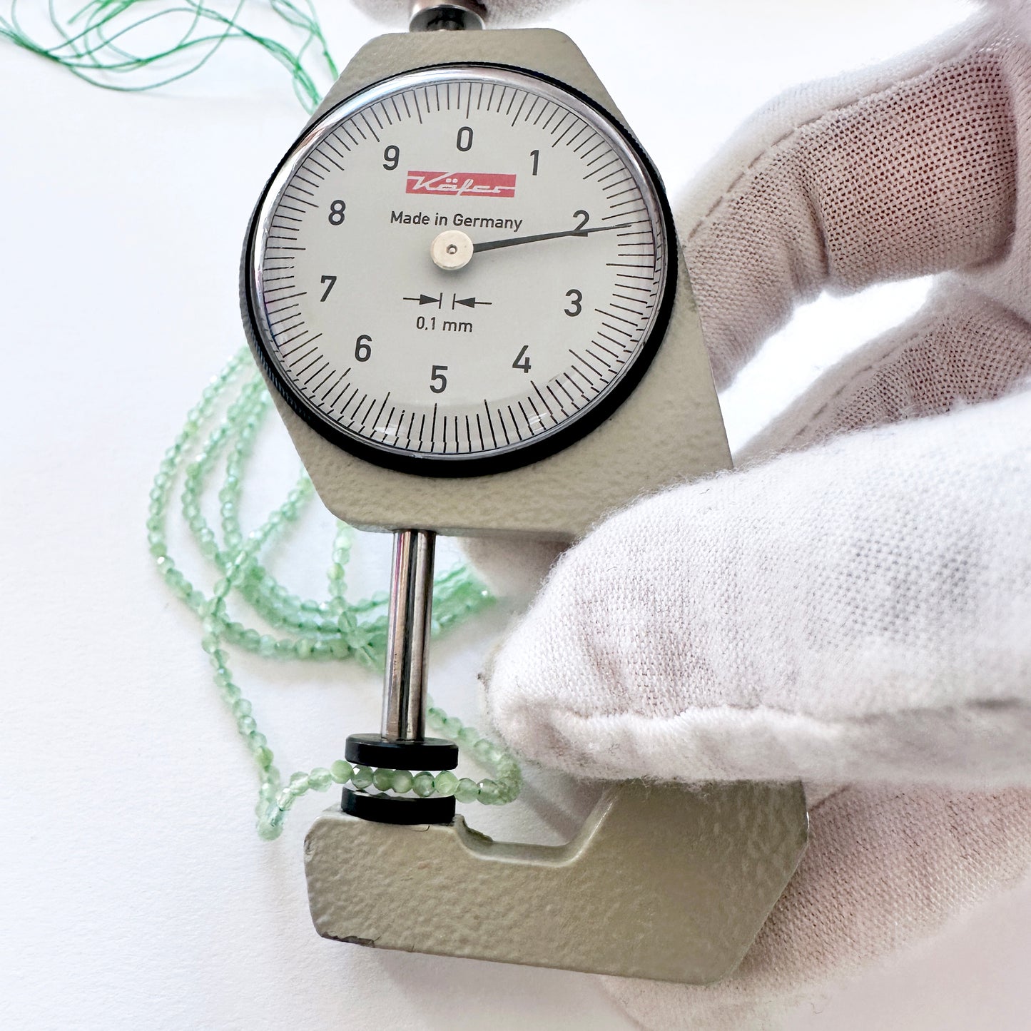 A dial gauge measures the Green Chalcedony faceted rondelle 2.1-2.2mm gemstone.