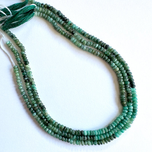Close-up of natural gemstone beads showing smooth rondelle cut and rich emerald colour.
