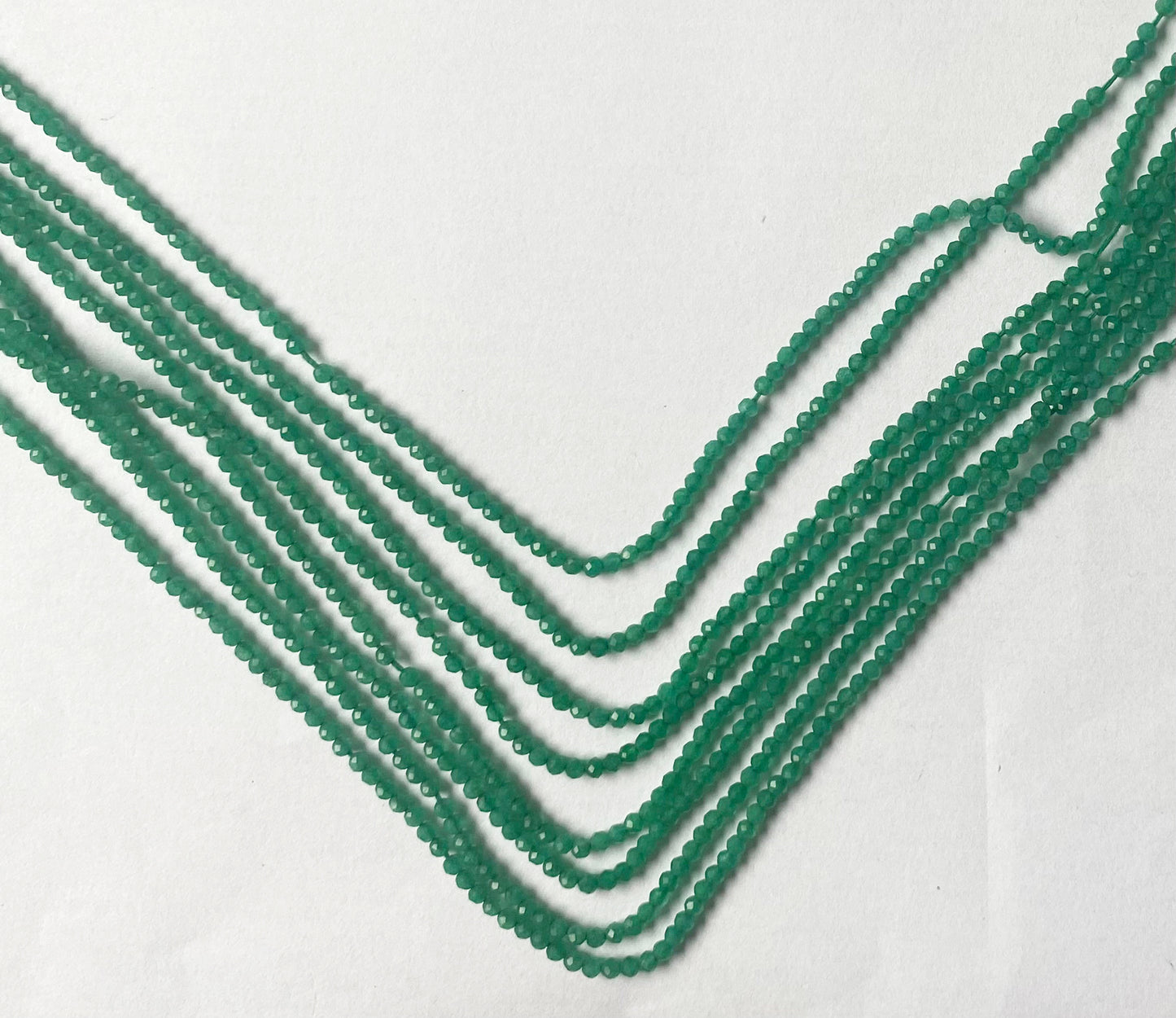 Radiant micro-faceted rondelle beads showcasing a brilliant emerald-green glow and refined shimmer.
