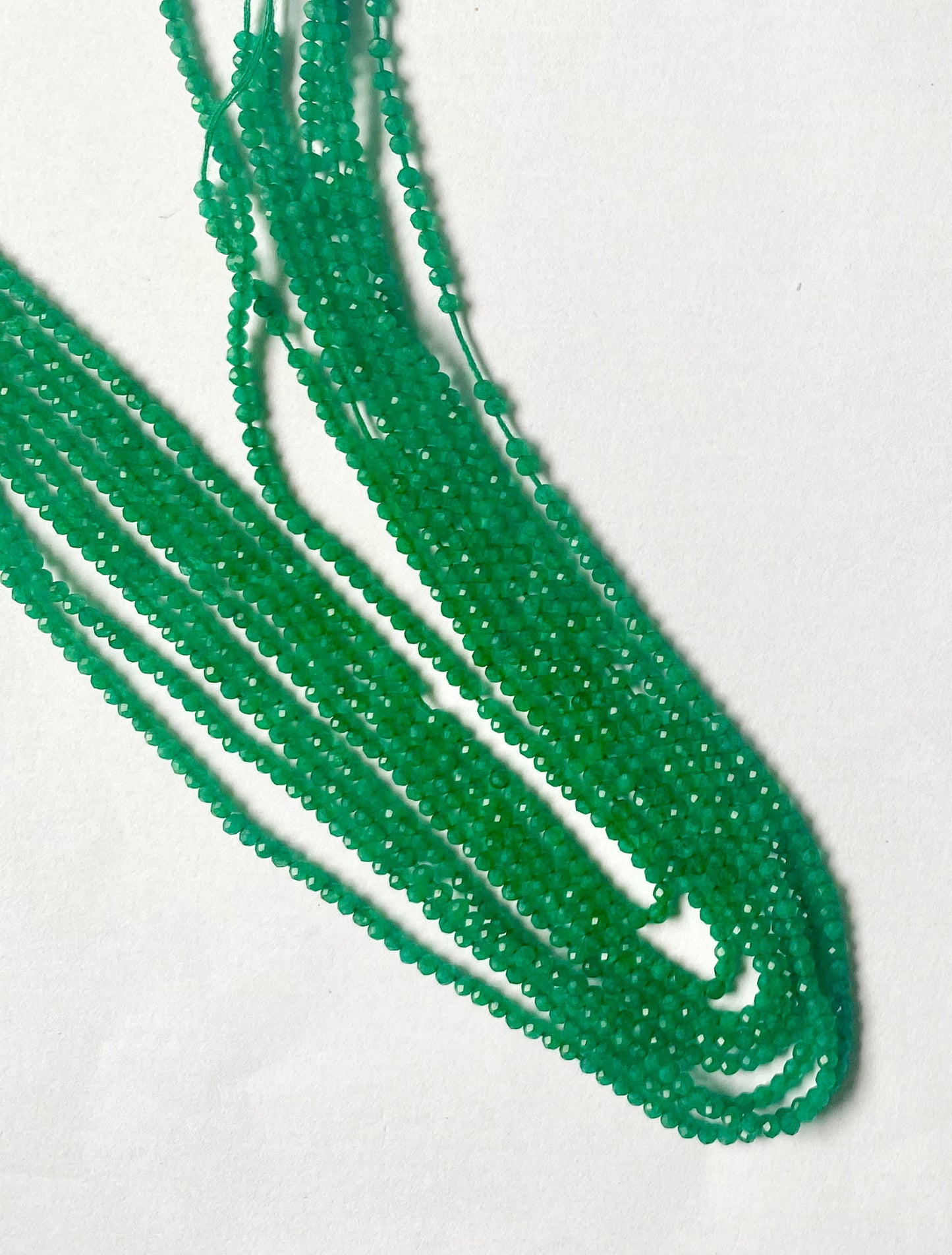 A close-up of Green Onyx beads displaying precise faceting and smooth edges.