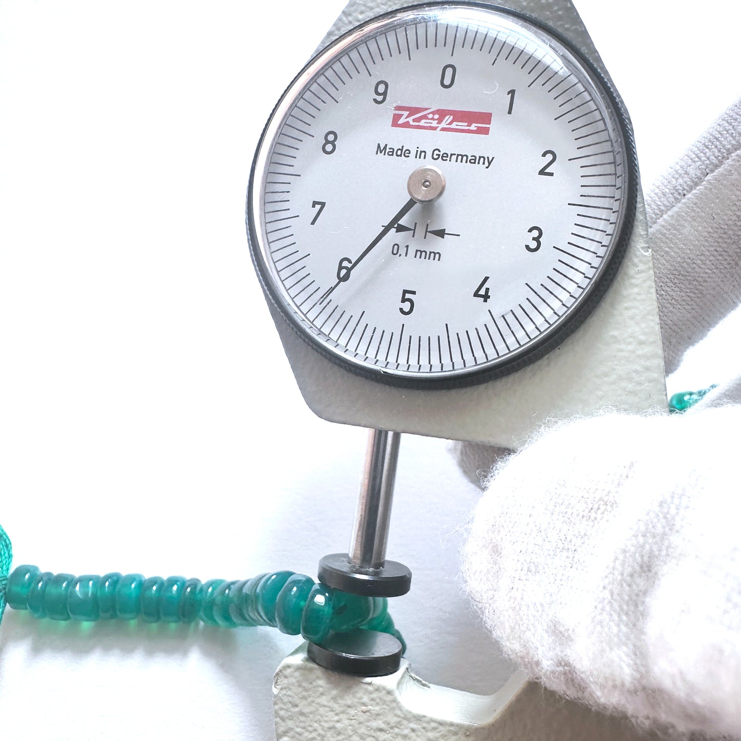 A dial gauge measures the Green Onyx smooth wheel 6mm gemstone.