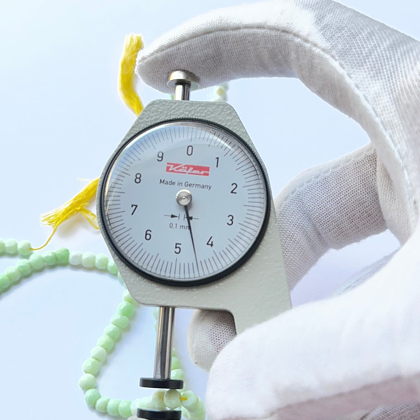 A dial gauge measures the Green Opal faceted rondelle 4.3–4.5mm gemstone.