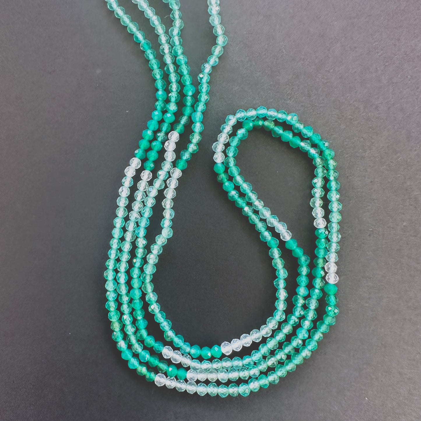 Close-up of Green Shaded Onyx faceted rondelle beads with gradient green tones and sparkling facets.