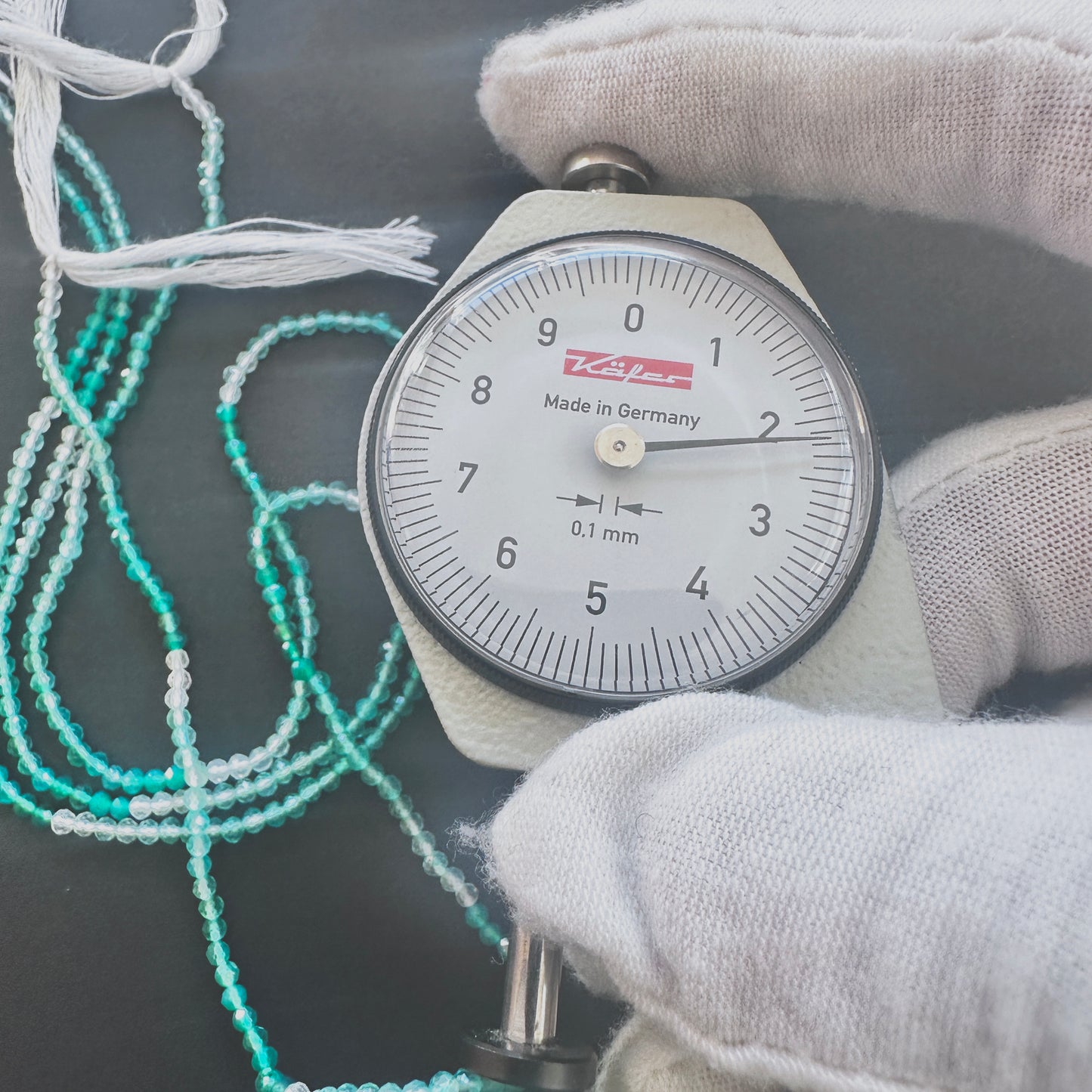 A dial gauge measures the Green Shaded Onyx faceted rondelle 2.2mm gemstone.