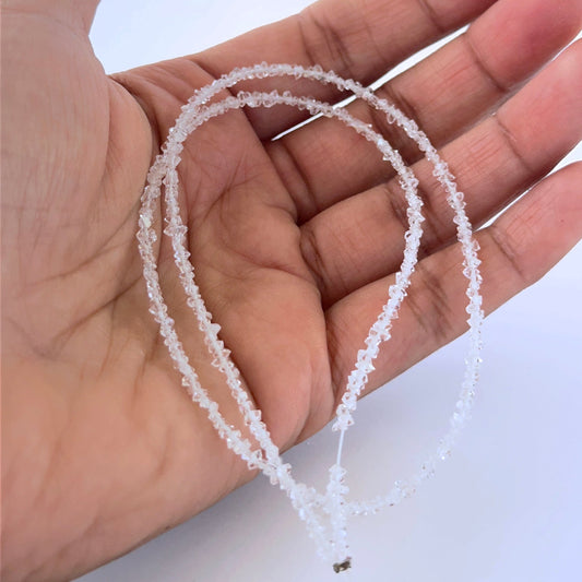 A person holds delicate strands of Herkimer Diamond chips, showcasing their natural shape.