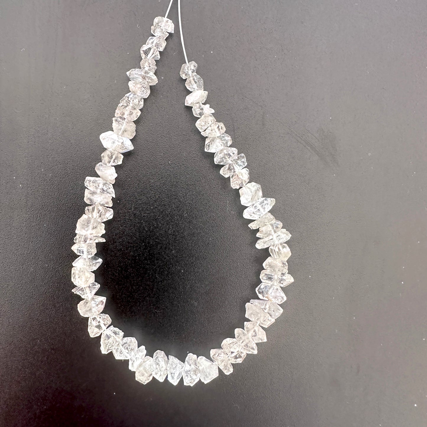 Herkimer Diamond rough beads with natural clarity and centre-drilled holes, arranged in a 57-piece pack.