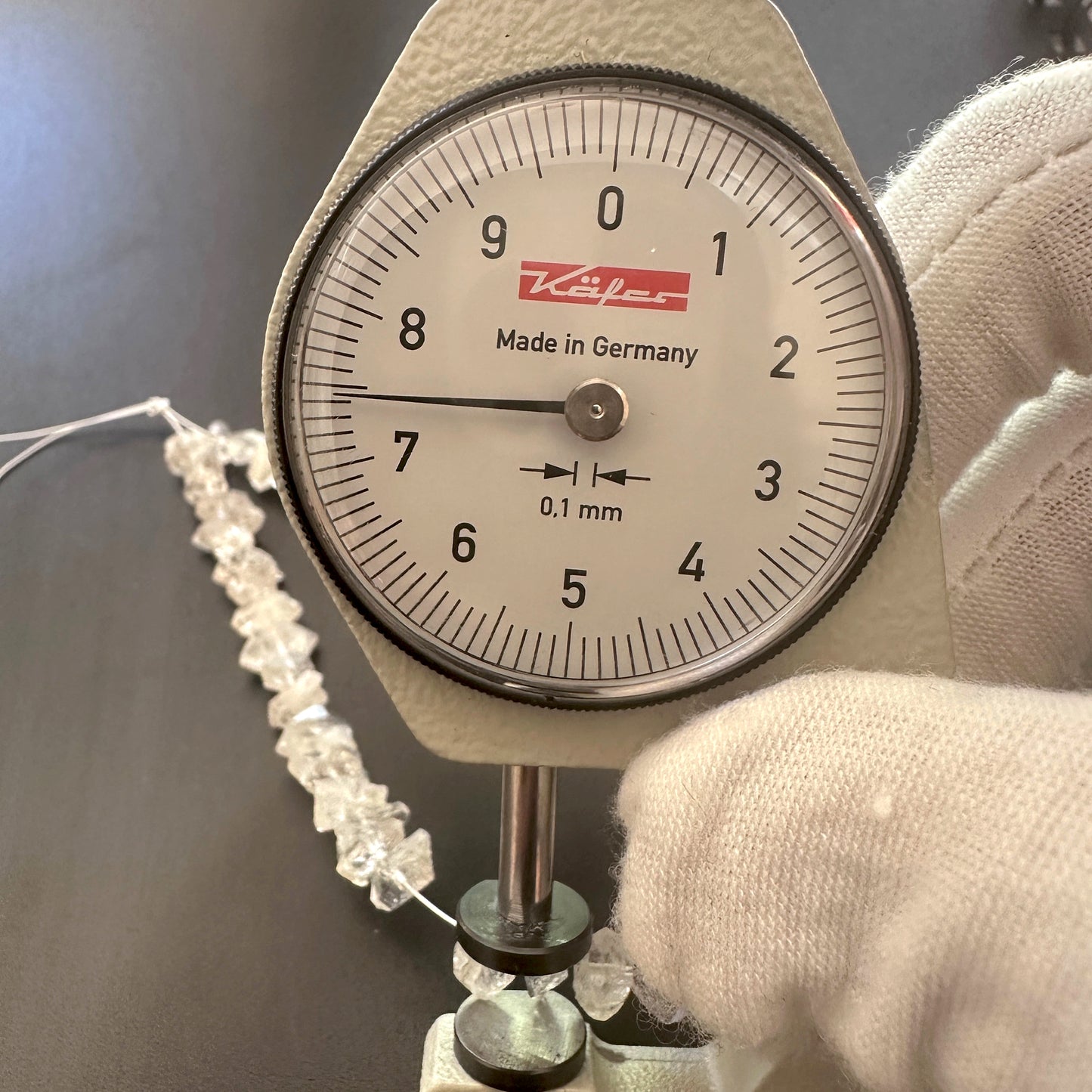 A dial gauge measures the Herkimer Diamond rough cut 4.5-5mm gemstone.