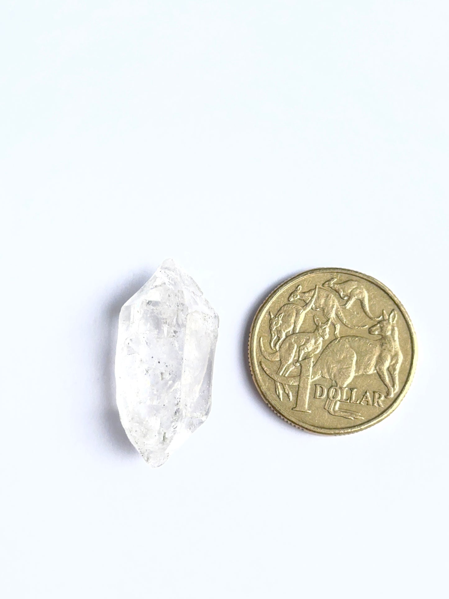 Herkimer Diamond rough photographed to show its unpolished finish and genuine brilliance and next to a coin for scale.