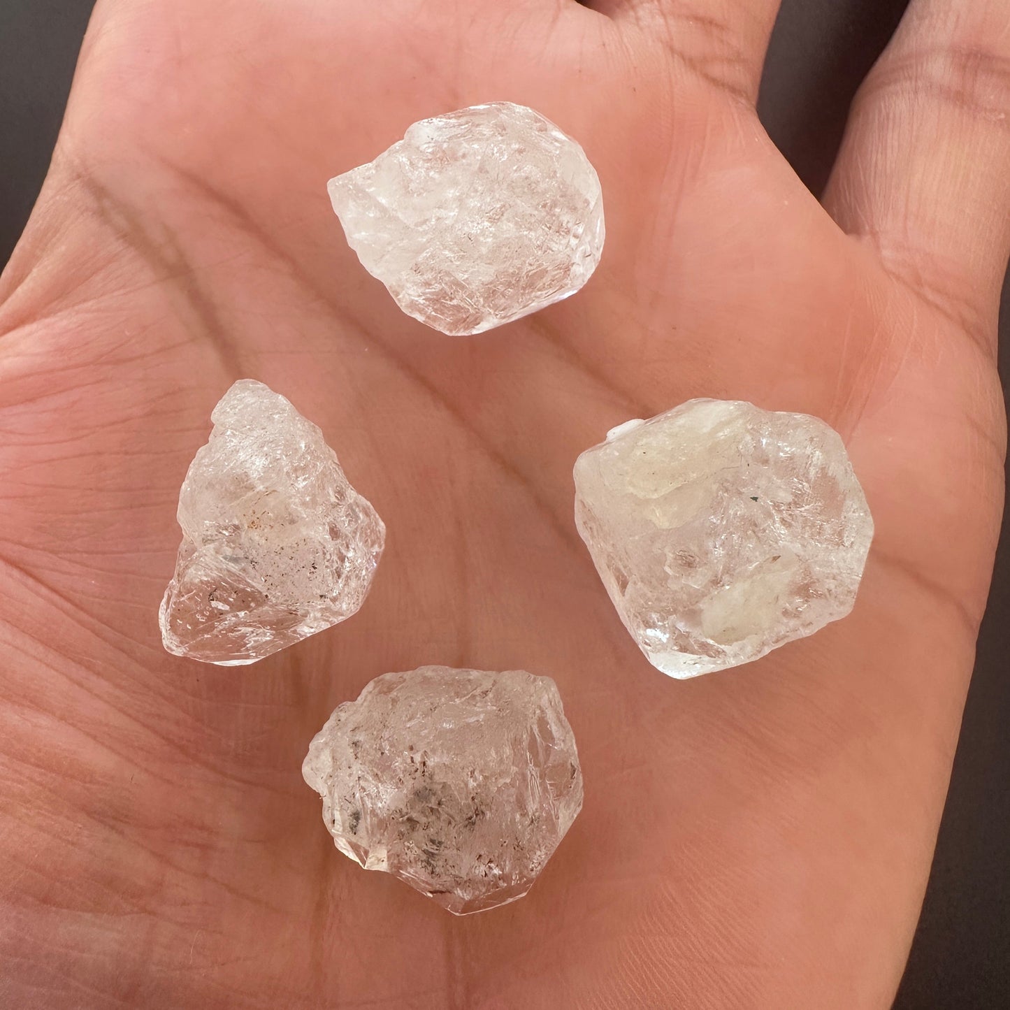 A person holds delicate strands of Herkimer beads, showcasing their rough organic design.