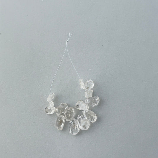 Close up of 14 piece Herkimer Diamond strand showing raw crystal geometry and 0.5mm drill holes