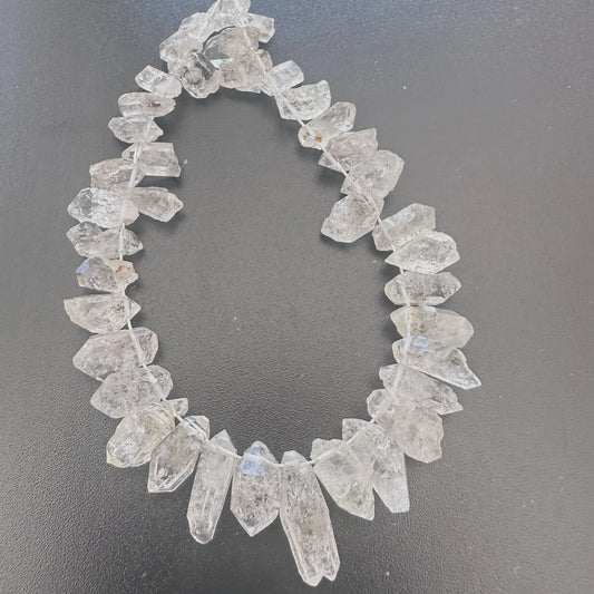 A close-up of Herkimer diamond beads showing rough side-drilled cuts and natural clarity.