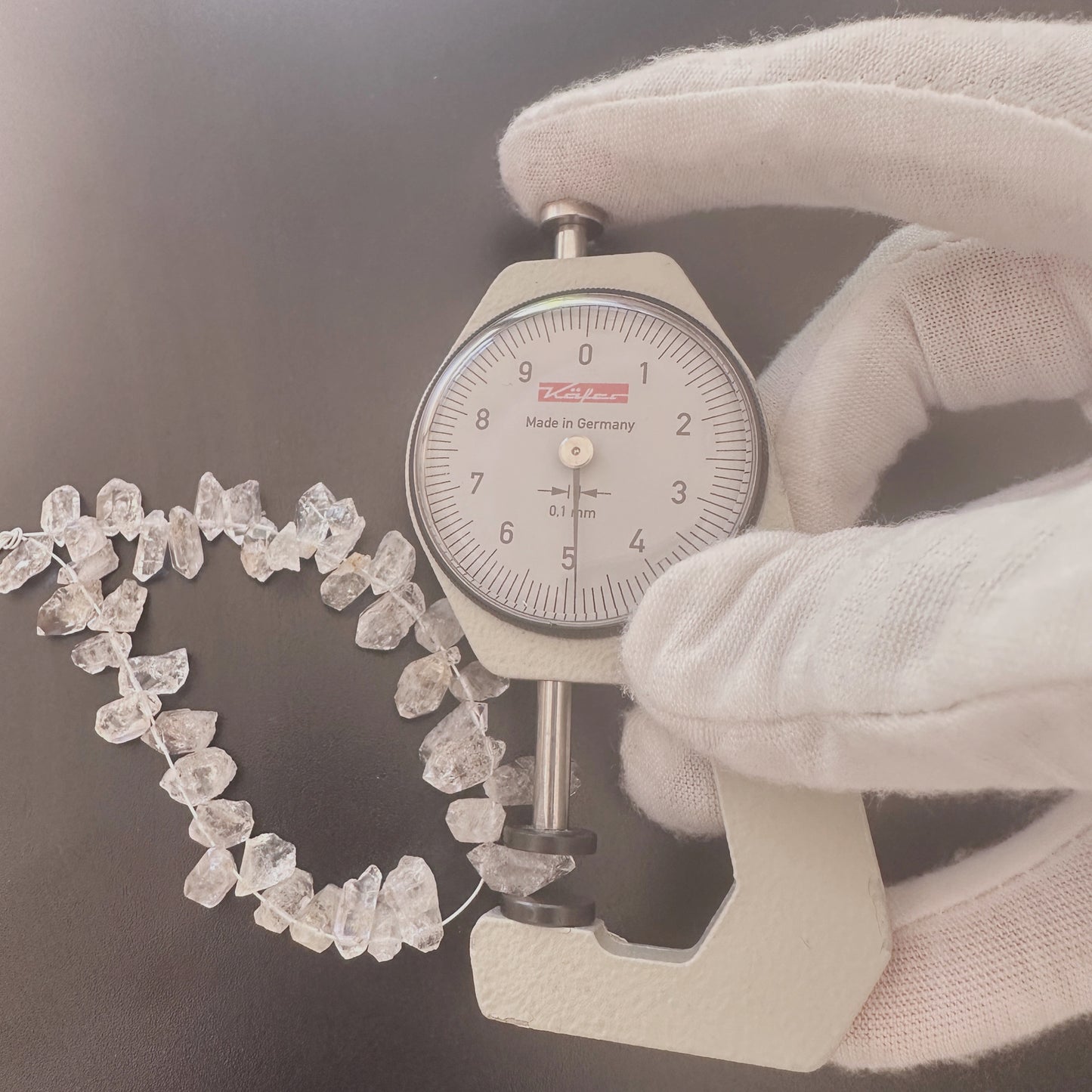 A dial gauge measures the Herkimer rough cut 4–5mm gemstone.