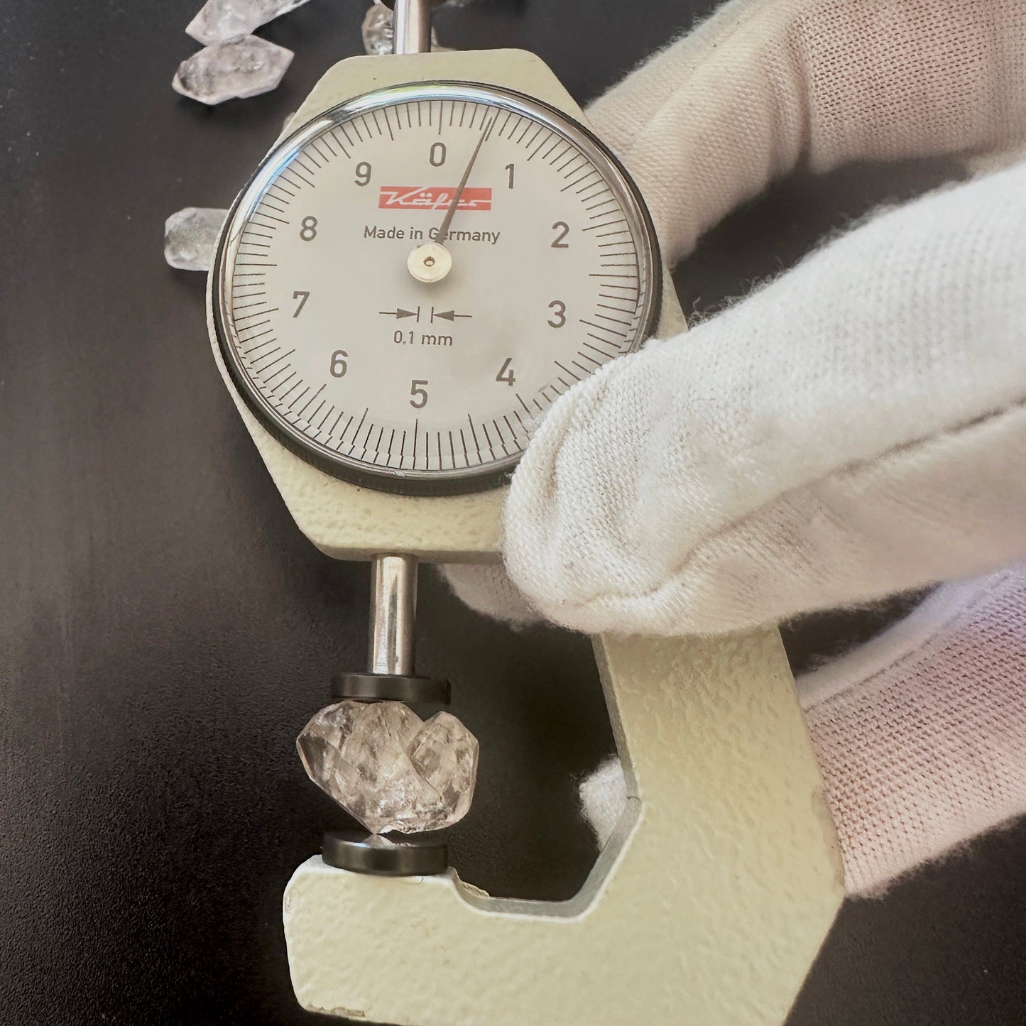 A dial gauge measures the Herkimer nugget rough cut gemstone.