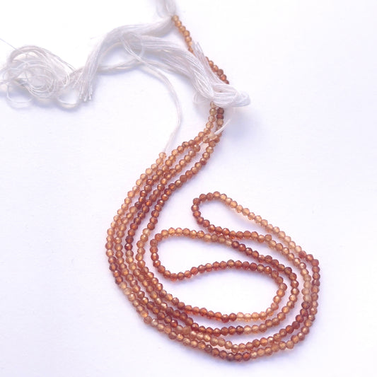 Close-up of natural gemstone beads showing faceting and rich hessonite colour.