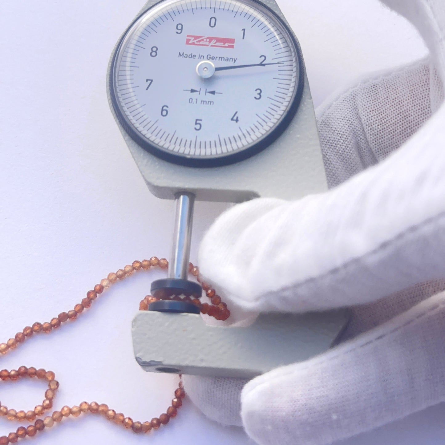 A dial gauge measures the hessonite faceted rondelle 2–2.2mm gemstone