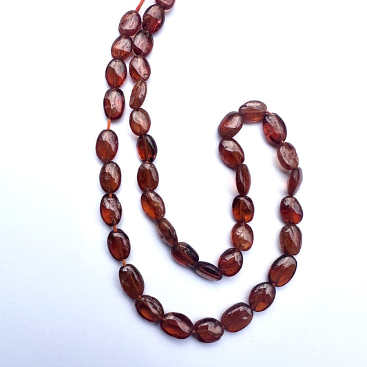 Close-up of natural gemstone beads featuring Hessonite in warm amber tones and polished finish.