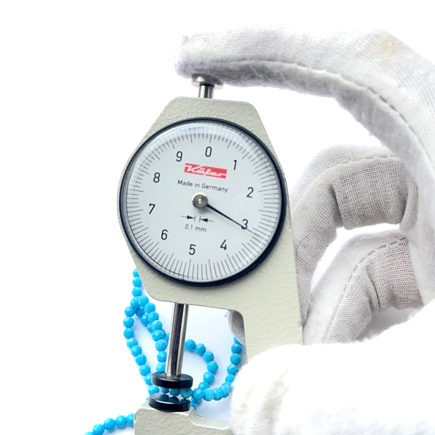 A dial gauge measures the howlite turquoise faceted rondelle 3.1mm gemstone.