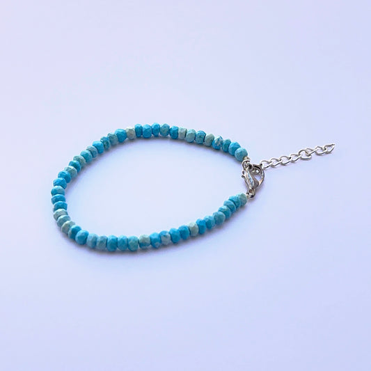 Close‑up of faceted howlite turquoise beads arranged on a polished bracelet.